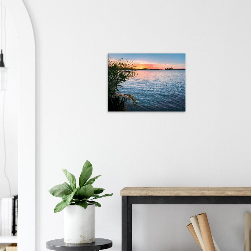 Mockup: Sonnenuntergang über dem See von Flores mit ruhigem Wasser, warmem Himmel und Palmen im Vordergrund.