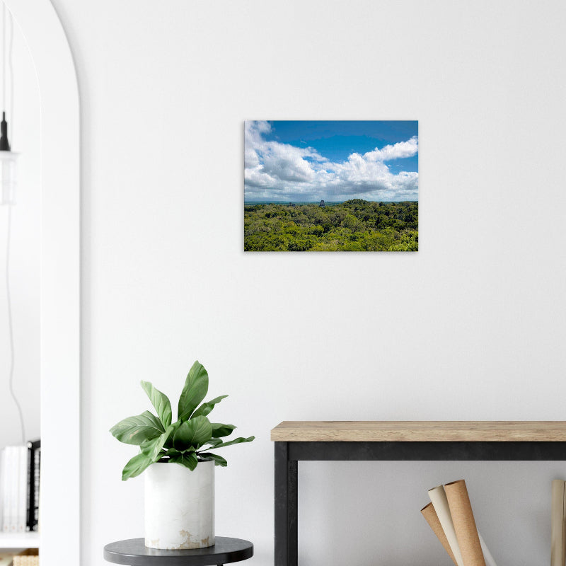 Mockup: Blick über den tropischen Regenwald von Tikal mit aus dem Blätterdach ragenden Maya-Tempeln unter blauem Himmel.