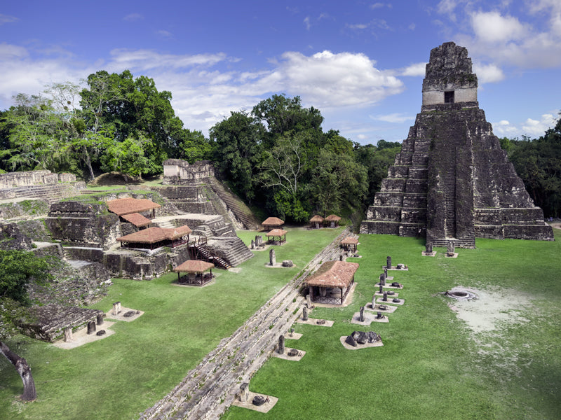 Weitwinkelaufnahme von Maya-Tempeln und Plätzen in Tikal, umgeben von dichtem Regenwald.